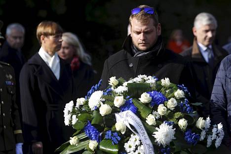 Mies kantoi kukkalaitetta muistomerkille Tallinnassa.