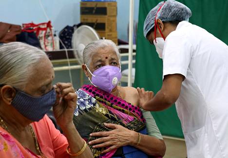 Hansa Pandhi, 76, odotti omaa vuoroaan, kun Pramila Shahia, 82, rokotettiin Mumbaissa keskiviikkona. Naiset saivat annokset Intiassa kehitettyä Covishield-rokotetta.