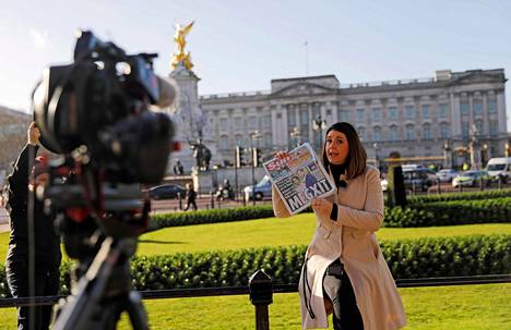 Harryn ja Meghan päätös aiheutti mediamylläkän Isossa-Britanniassa. Kuvassa toimittaja pitelee päivän lehteä raportoidessaan tilanteesta Buckinghamin palatsin edustalta torstaina 9. tammikuuta.