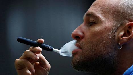 Mies polttaa Philip Morrisin IQOS-tupakointilaitteelle Bogotassa Kolumbiassa.