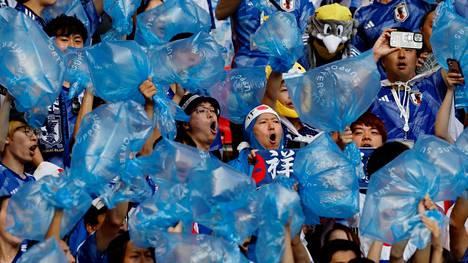 Japanin kannattajat puhaltavat muovisäkkeihin ilmaa ottelujen aikana. Ottelun jälkeen säkit ovat roskien keräämiseen.