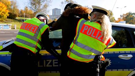 Saksalaispoliisit tutkivat laitonta siirtolaista Frankfurtin rajalla.