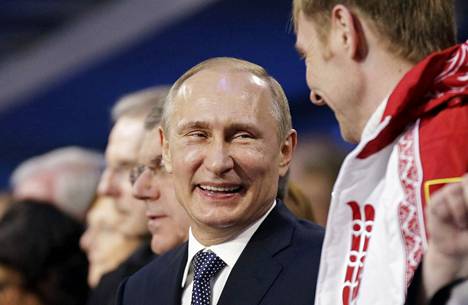 Presidentti Putin nauraa Venäjän kultamitalisti rattikelkkaurheilijan Alexander Zubkovin kanssa vuoden 2014 Sotshin talviolympialaisten päätösseremoniassa 23.2.2014.