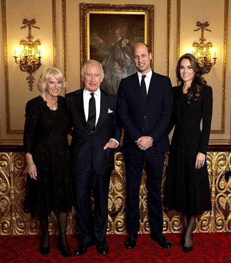 Kuninkaalliset hymyilevät kuvassa mustiin pukeutuneina.