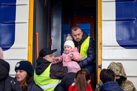 Työntekijät auttavat nostamaan taaperoa junaan Lvivin rautatieasemalla.