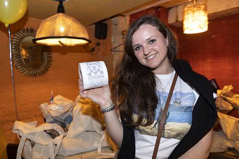 Lahjoittajille kangaskasseja jakava Kristina esittele kasseista löytyvää Putin-vessapaperirullaa.
