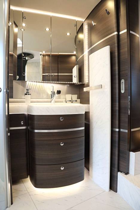 Pesutiloissa on marmorimaista pintaa ja lasiset ovet. Kylpyhuoneen vaalea seinäelementti on lämmityspatteri.