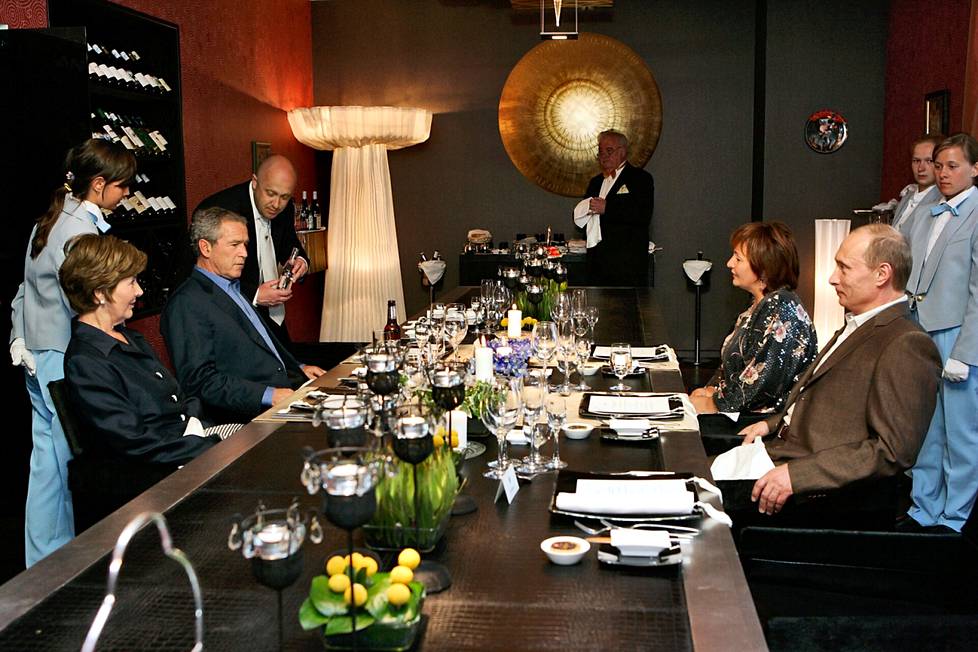 Laura ja George W. Bush nauttivat Ljudmila ja Vladimir Putinin seurasta pietarilaisravintolassa heinäkuussa 2006. Bushin lasiin vettä kaatoi ravintolan omistaja, kaljupäinen mies, josta kuultaisiin vielä myöhemmin.