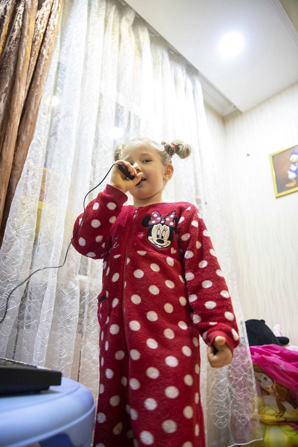 6-vuotias Alisa järjesti Ilta-Sanomien kuvaajalle esityksen sähkökäyttöisellä karaokelaitteellaan.