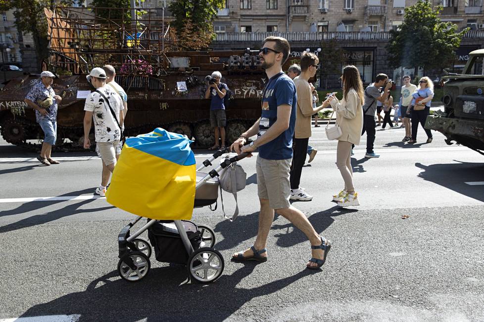 Mies kulkee Ukrainan lipulla suojattujen rattaiden kanssa itsenäisyyspäivänä järjestyssä paraatissa Kiovassa.