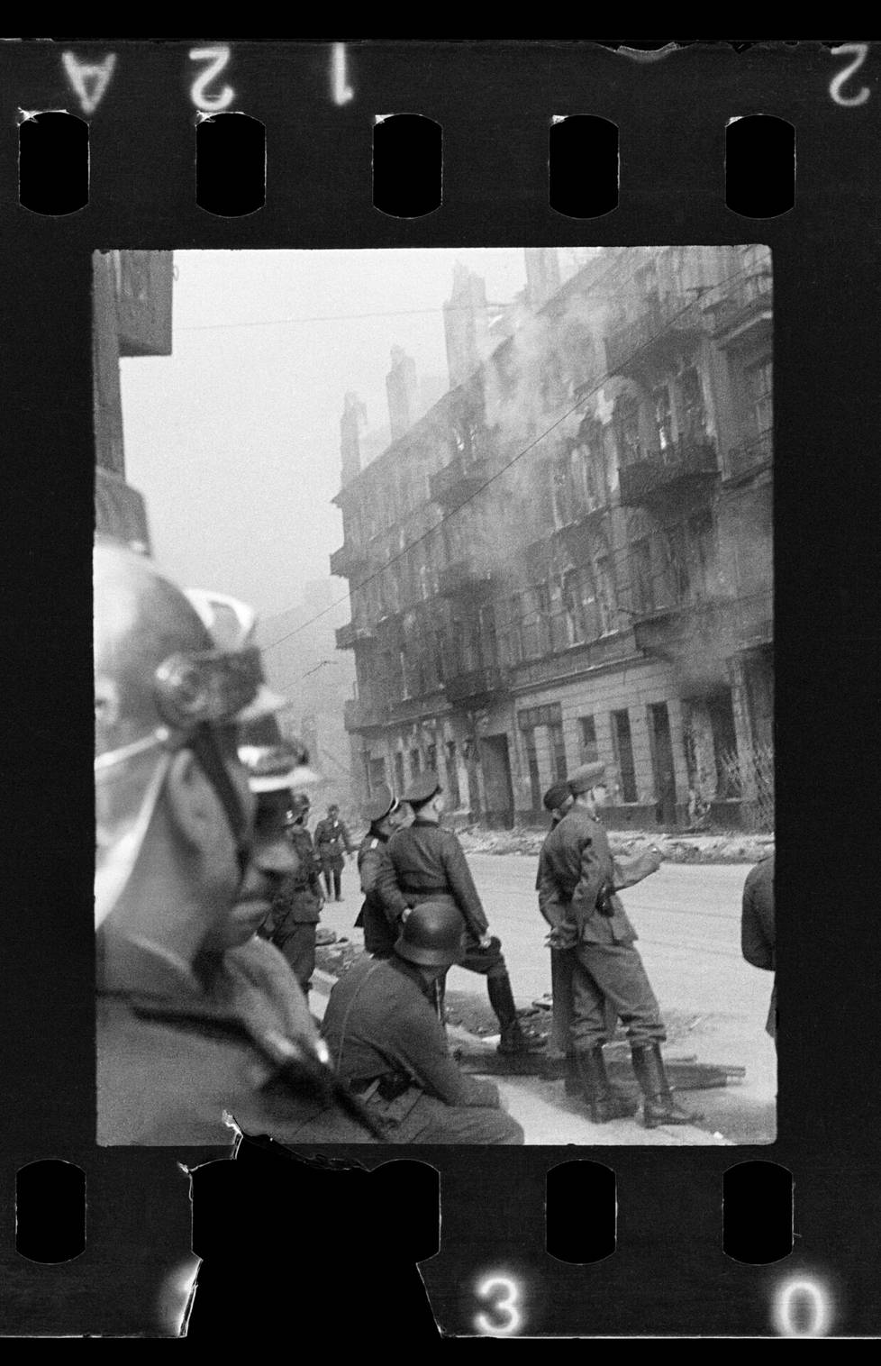 Puolalaiset palomiehet saattoivat vain seurata vierestä, kuinka saksalaiset polttivat gettoa. Kuva on otettu Nowolipie-kadulla huhtikuussa 1943.