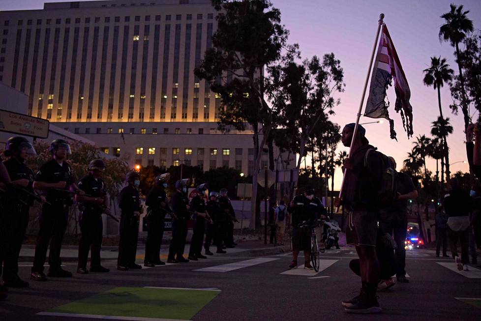 Mielenosoittaja uhmasi poltetun lipun kanssa poliisirivistöä Los Angelesissa, jossa protestoitiin aseettoman mustan miehen George Floydin kuolemaa poliisin käsissä aiemmin tällä viikolla Minneapolisissa. Eri puolilla maata on puhjennut jopa väkivaltaisia mellakoita, joissa on poltettu rakennuksia ja autoja.
