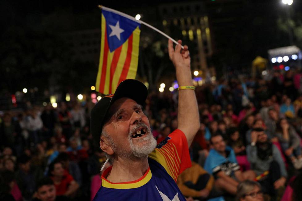 Mies liehutti Katalonian lippua illalla Barcelonan Plaza Catalunya -aukiolla, jonne ihmiset kerääntyivät juhlistamaan kansanäänestystä.