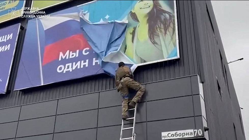 Ukrainalaissotilas repi alas venäläistä propagandajulistetta Vovtshanskissa syyskuussa 2022. Kaupunki oli palautettu Ukrainan armeijan kontrolliin muutamaa päivää aiemmin.