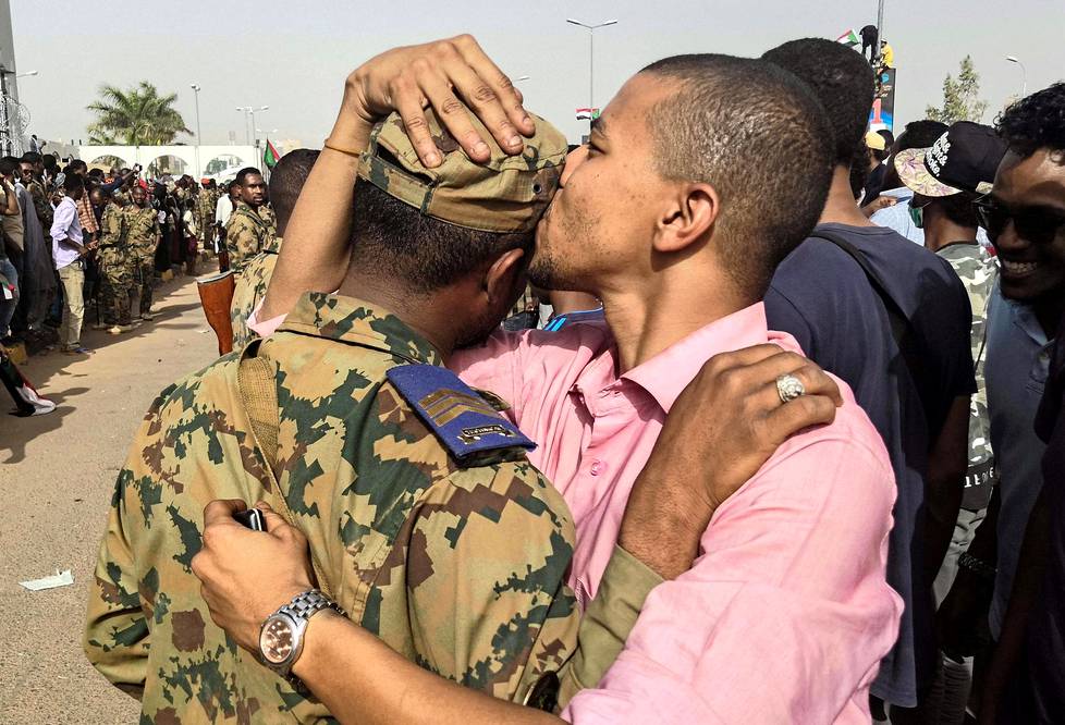 Voitto!  Sudanilaismies nappasi sotilaan syleilyyn hallituksen vastaisessa mielenosoi tuksessa Khartumissa, kun armeija kertoi syrjäyttäneensä presidentti Omaral-Bashirin.