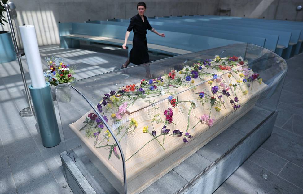 Kuin lumikki. Berliiniläinen hautausurakoitsija valmisteli koronauhrin hautajaisia, joissa arkku on hygieniavarotoimien takia lähinäkyvässä kotelossa.