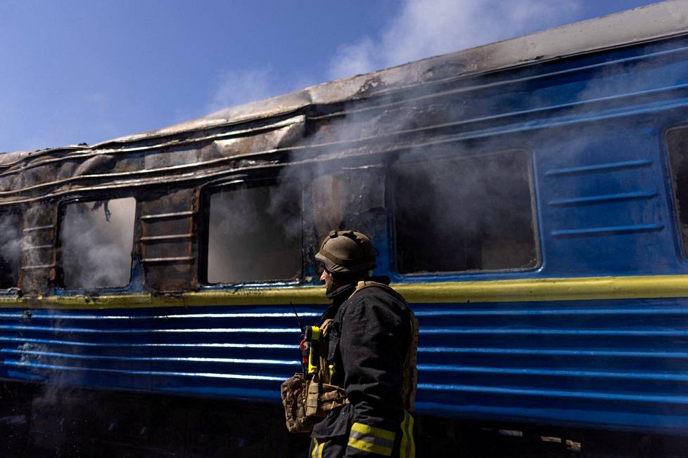 Ukrainalainen pelastustyöntekijä sammuttaa Venäjän iskun jäljiltä savuavaa junavaunua Hersonissa toukokuussa 2023.