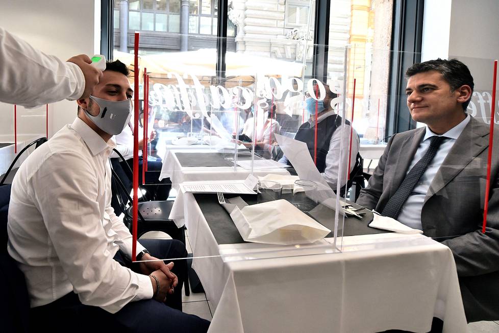 Ravintolakuumetta? Tarjoilija mittasi asiakkaan lämmön Milanossa, Italiassa, kun ravintolat saivat avata ovensa tiukkojen koronaturvatoimien kera.